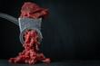 Making minced meat for beef meatballs in a manual meat grinder on a black background. Macro shot. Close up of metal meat grinder with raw meat