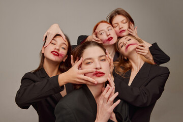 Wall Mural - Portrait of young beautiful women in black jackets and red lipstick makeup posing over grey background. Unusual look