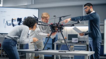 Poster - Young Specialists Connecting Drone to a Laptop. Engineers Try to Make Jobs Safer, Easier and More Efficient by Automated Contactless Delivery Machines. Professionals Work in Aviation Industry.