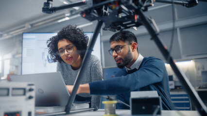 Poster - Black Male Engineer Points at Laptop Screen and Talks. Brainstorming New Drone Design With his Female Colleague. Innovative Technologies in Unmanned Aerial Vehicle Design Concept.