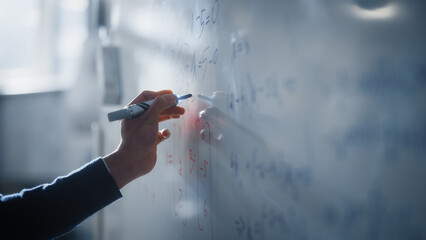 Macro Shot of a Blue Marker Pen Being Held with a Hand. Teacher Writing Equations on a Whiteboard with Mathematical Formulas. Higher Education in University of Technology Concept.
