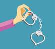 Woman holds a handcuff in the shape of a heart.