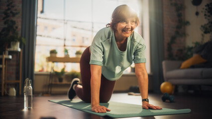 Wall Mural - Strong Fit Senior Woman Training on a Yoga Mat, Doing Stretching and Core Strengthening Exercises During Morning Workout at Home in Sunny Apartment. Health and Fitness Concept.