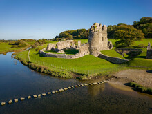Aerial View Of Stepping Stones Crossing A Small River Leading To An Ancient Ruined Castle (Ogmore, Wales)