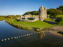 Aerial View Of Stepping Stones Over A Small River Leading To The Ruins Of An Ancient Castle (Ogmore Castle, Wales)