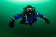 SCUBA diver in a drysuit and rebreather underwater in a cold, dark, murky quarry