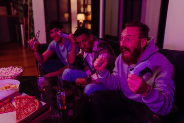 Poster - Three male friends playing video games and drinking beer in dark living room