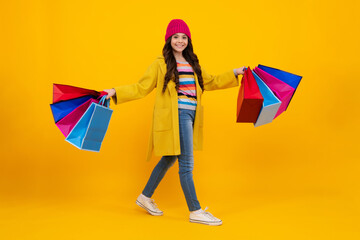 Canvas Print - Beautiful fashion teenager child girl with shopping bags on yellow background. Shopaholic shopping and fashion. Kid with shopping sale bags. Happy teenager, positive and smiling emotions.