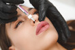 © inna717 - female lips, lip augmentation procedure. A syringe near a woman's mouth, injections to increase the shape of the lips