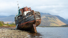 The Corpach Wreck.  A Wrecked And Abandoned Trawler On The Banks Of Loch Eil, North West Scotland With Ben Nevis Mountain In The Background.