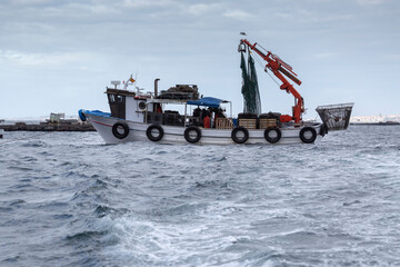 Traditional wooden fishing boat working in the mussel farming rafts of the estuary