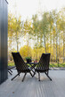Two dark wooden chairs on the veranda. Landscape autumn. Vertical