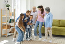 Happy, Cheerful Family Goofing Around Together. Children, Parents And Grandparents Having Fun At Home. Joyful Father Hugging His Son While The Rest Of The Family Are Standing Around And Smiling