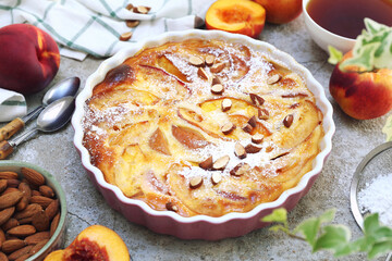 Wall Mural - Nectarine clafoutis (flan) with almonds, icing sugar dressing and cup of tea