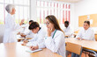 © JackF - Latin woman medical student sitting at desk in classroom during lecture in medical college with group of students.