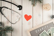 Abstract composition nameplate charity with money, stethoscope, red heart and spruce twigs as decoration on wooden view