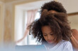 © KAMPUS - Supportive mother brushing daughters hair. African American family spending time together, girl using mobile phone. Family, hairstyle, care, technology concept
