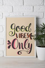 Wall Mural - Board with phrase Good Vibes Only and houseplant on wooden table near white brick wall