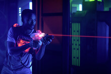 Laser Tag Player Holding Gun Shooting Light In Black Light Labyrinth