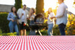 © New Africa - Empty table and blurred view of friends having barbecue party outdoors. Space for text
