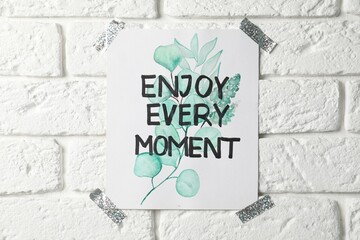 Wall Mural - Card with phrase Enjoy Every Moment attached on white brick wall