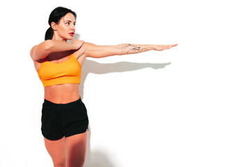 Wall Mural - Portrait of fitness confident woman in black sports clothing. Sexy young beautiful model with perfect body. Female isolated on white wall in studio. Stretching out before training