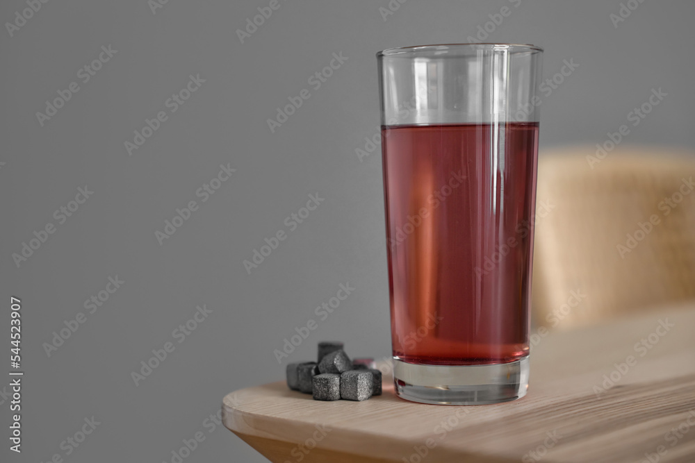 Glass of water with soluble tablets on table near grey wall