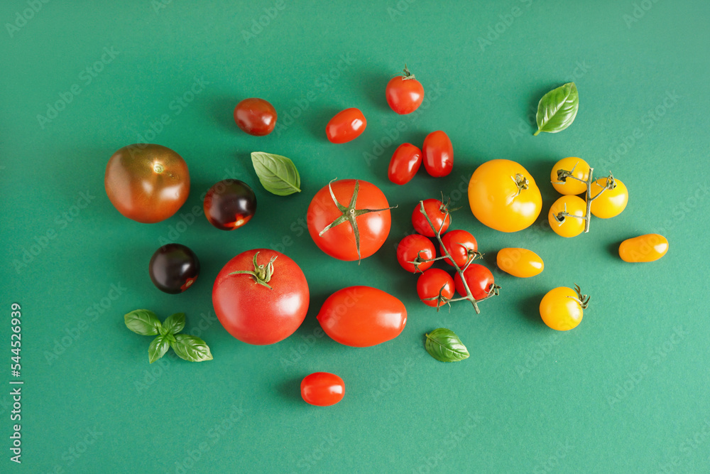 Different fresh tomatoes on green background