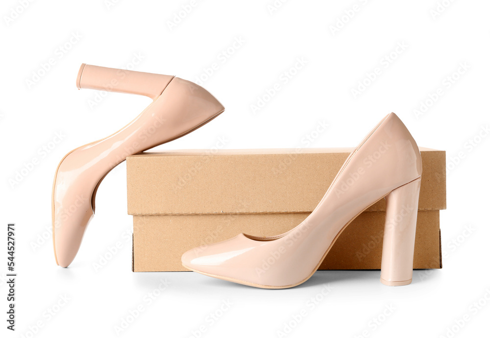 Cardboard box with beige high-heeled shoes on white background