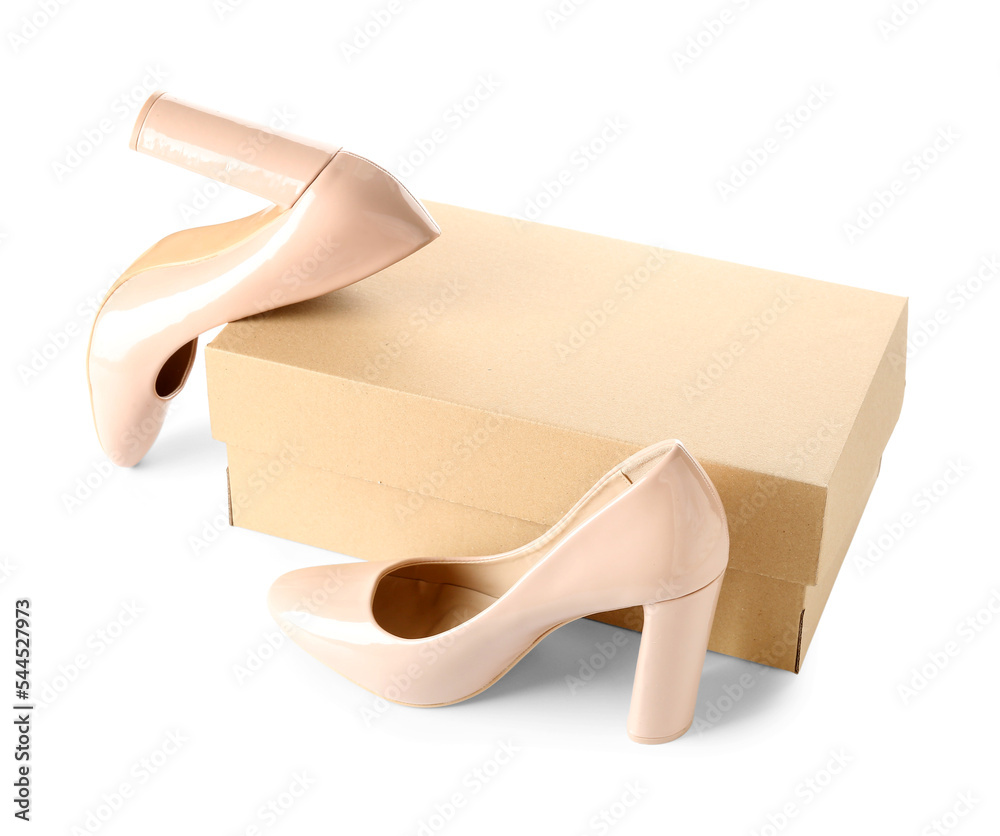 Cardboard box with beige high-heeled shoes on white background