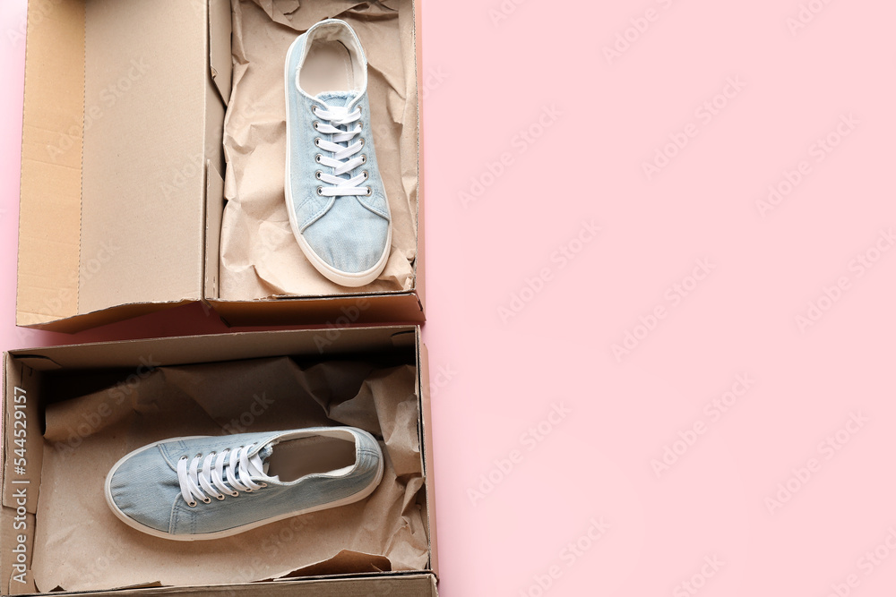 Cardboard box with blue sneakers on pink background