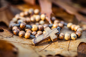 Wall Mural - Wooden rosary beads lying on autumn leaves.