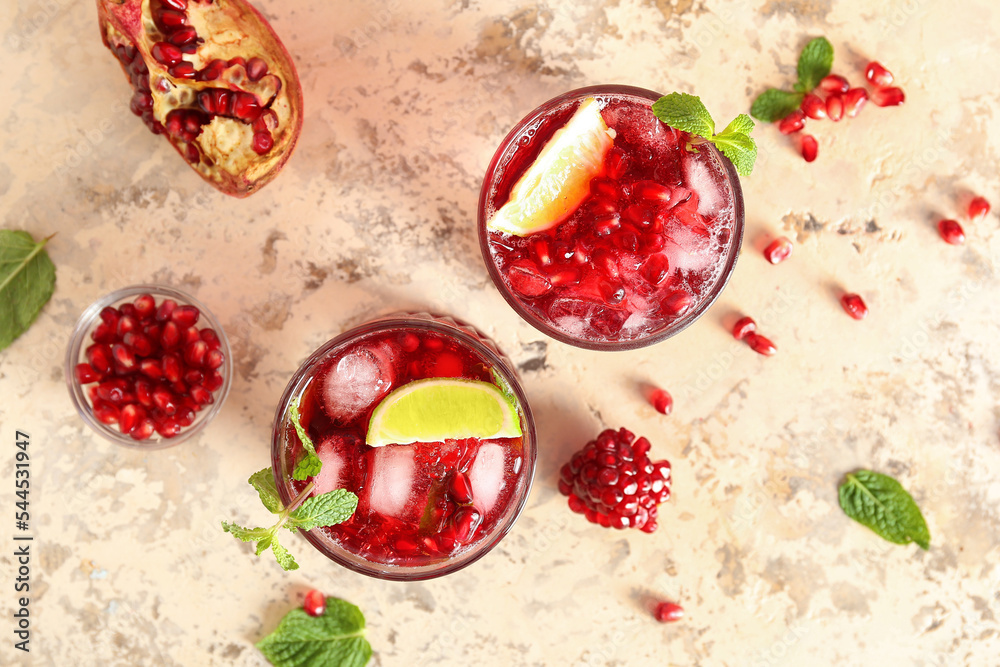 Glasses of cold pomegranate juice on color background