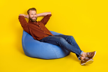 Canvas Print - Full size portrait of satisfied young man sitting comfy bag arms behind head isolated on yellow color background