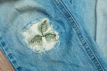 old worn jeans with a patch sewn in place of a hole.mending clothes concept.reusing old jeans.sustai