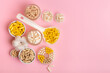 Organic food supplements in jars and small plates on pink background from above. Different vitamins and minerals to improve human`s health and immune system.