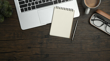 Above view of blank notepad, laptop, glasses and coffee cup and wooden working desk