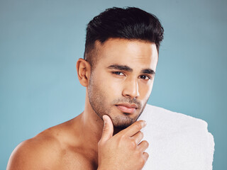 Poster - Man, hand on face and skincare cleaning or grooming cosmetics portrait in studio. Young Indian model, healthy facial care and body skin detox or wellness lifestyle treatment against blue background