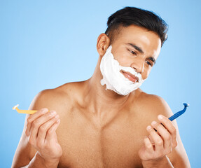 Poster - Man, razor and shaving in studio for choice, confused or thinking of skin, cosmetics or performance. Model, shaving cream or blade for shave, grooming or skincare for hair on face by blue background