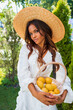 Portrait of a Beautiful African American girl in a hat and white dress holding a basket of lemons outdoors    