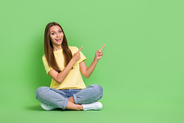 Poster - Photo of astonished lady sit floor two arm direct empty space cool proposition big black friday sales isolated on green color background