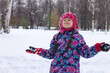 Happy little girl is enjoying winter and catching snowflakes with her hands in winter park
