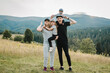 © Serhii - Mother, father hug childs in autumn. Family with kids hiking on grass on top of a mountains. Tourists enjoy valley view sunset. Mom, dad, son, and daughter. Holiday trip concept. World Tourism Day.