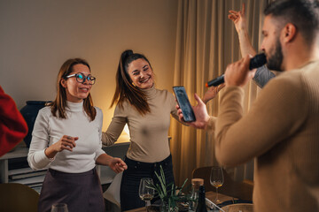 Wall Mural - friends singing karaoke at dinner party at home