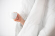 Early morning concept. A hand and a cup of coffee under the covers. White color.