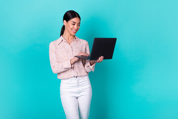 Wall Mural - Photo of cheerful pretty person toothy smile hands hold wireless netbook isolated on emerald color background