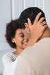 © LIGHTFIELD STUDIOS - joyful african american woman hugging head of young boyfriend in kitchen