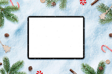 Poster - Tablet in snow for app design or copy promotion. Surrounded by Christmas decorations. Top view, flat lay