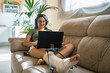 © Cavan Images - Young woman with broken leg lying on bed while using an laptop