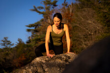 A Woman Climbing Onto A Rock With Long Hair.